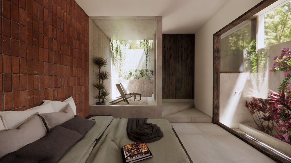 Bedroom opening through a wide reveal to a planted courtyard, with a brick wall behind the bed