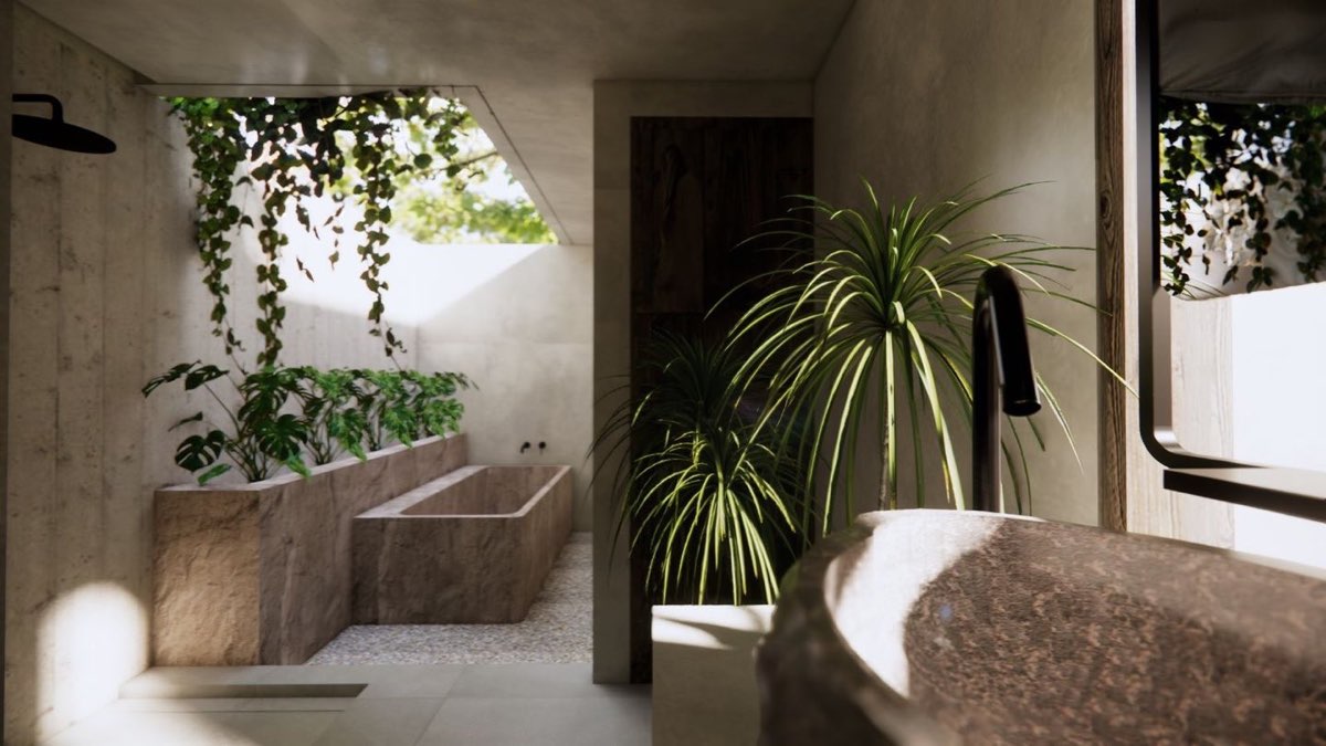 Open-air bathroom with a bath carved from a single block of stone, a rain head on a board-formed wall and planting along the sill