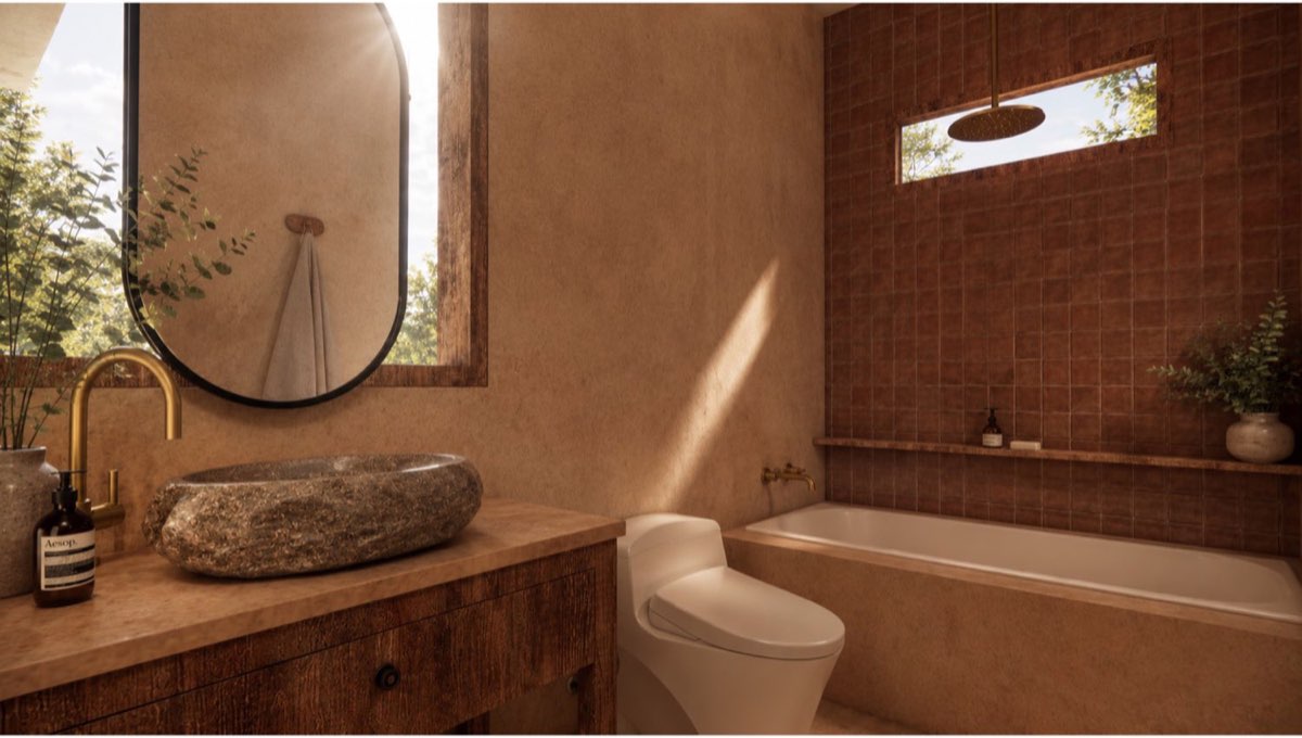 Bathroom with a carved stone basin on a timber vanity, round mirror, brass tapware and a bath under a clerestory window